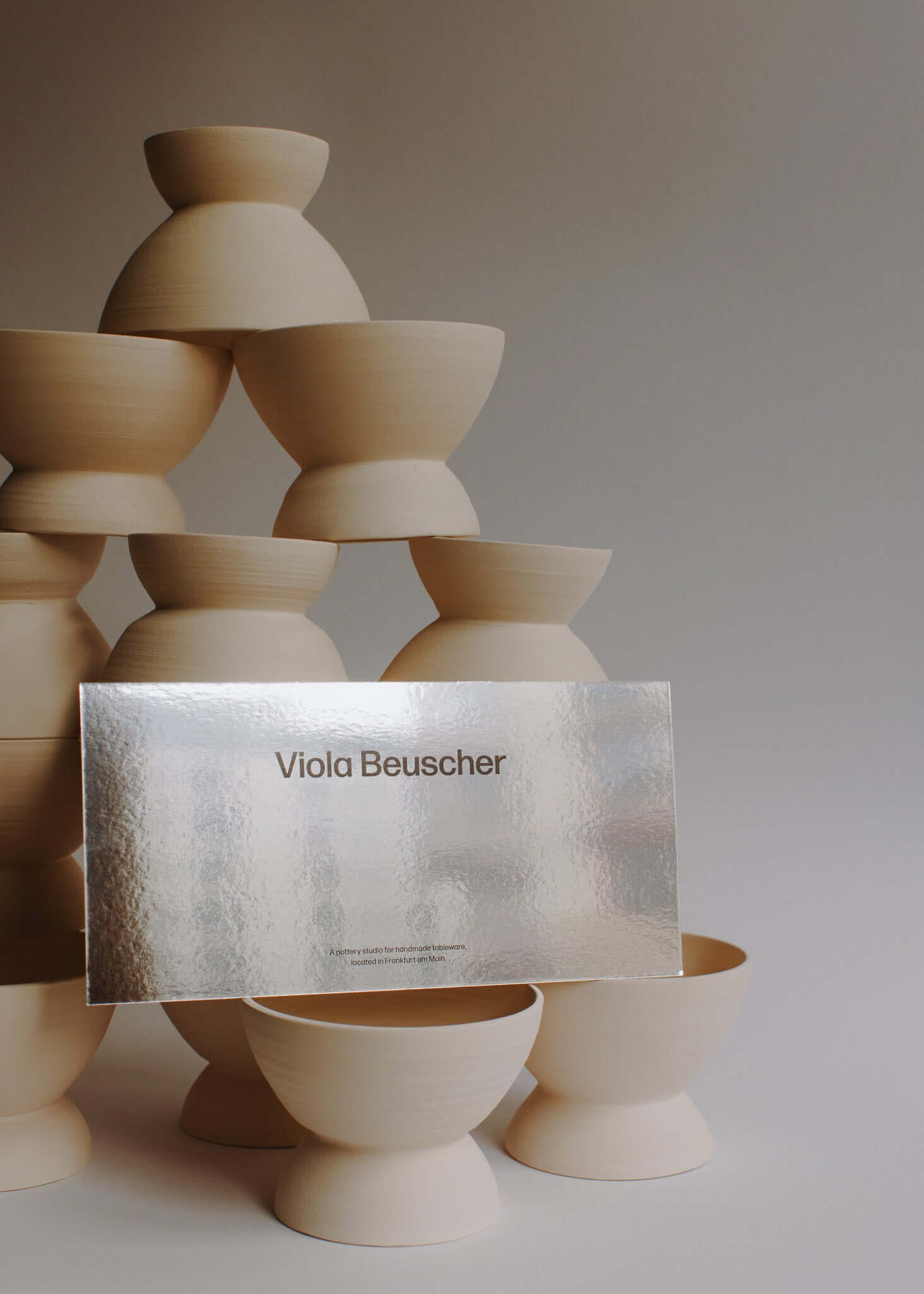 Printed gift card displayed in front of a stack of minimalist pottery bowls.