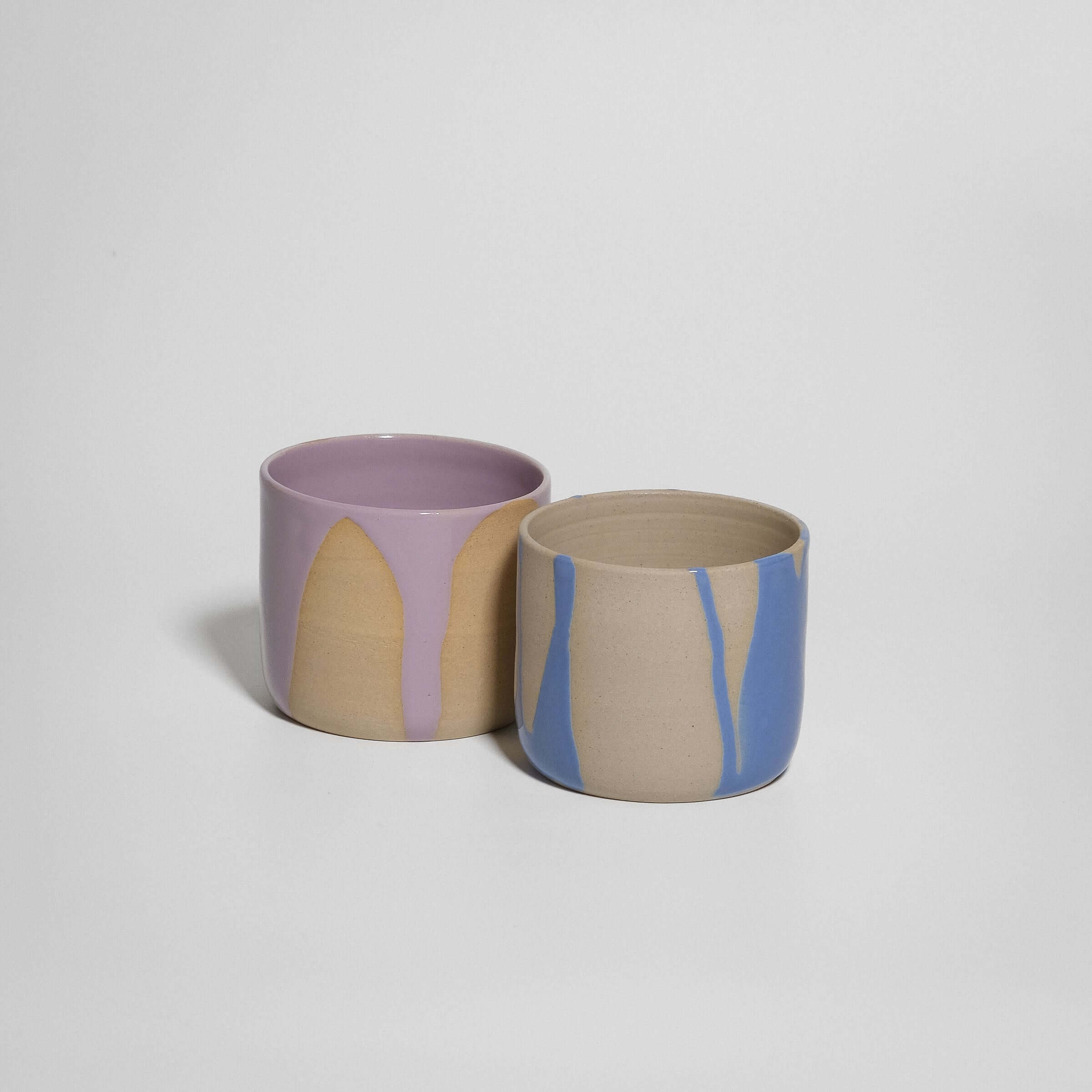 Handcrafted grey stoneware coffee cup set with glossy lilac and blue glazes, ideal for warm beverages.