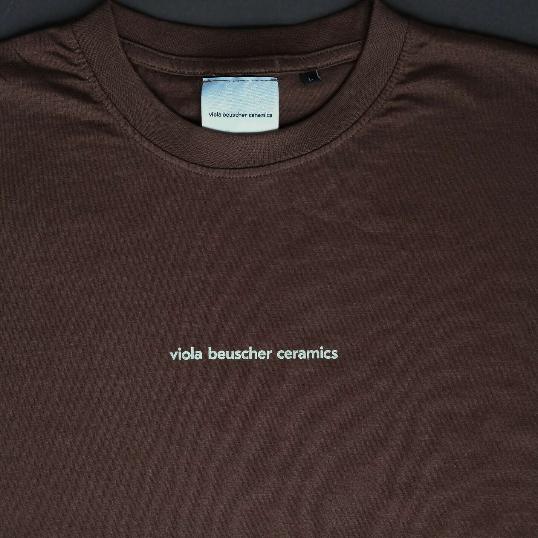 Chocolate T-shirt featuring white logo print 'viola beuscher ceramics' on the front.