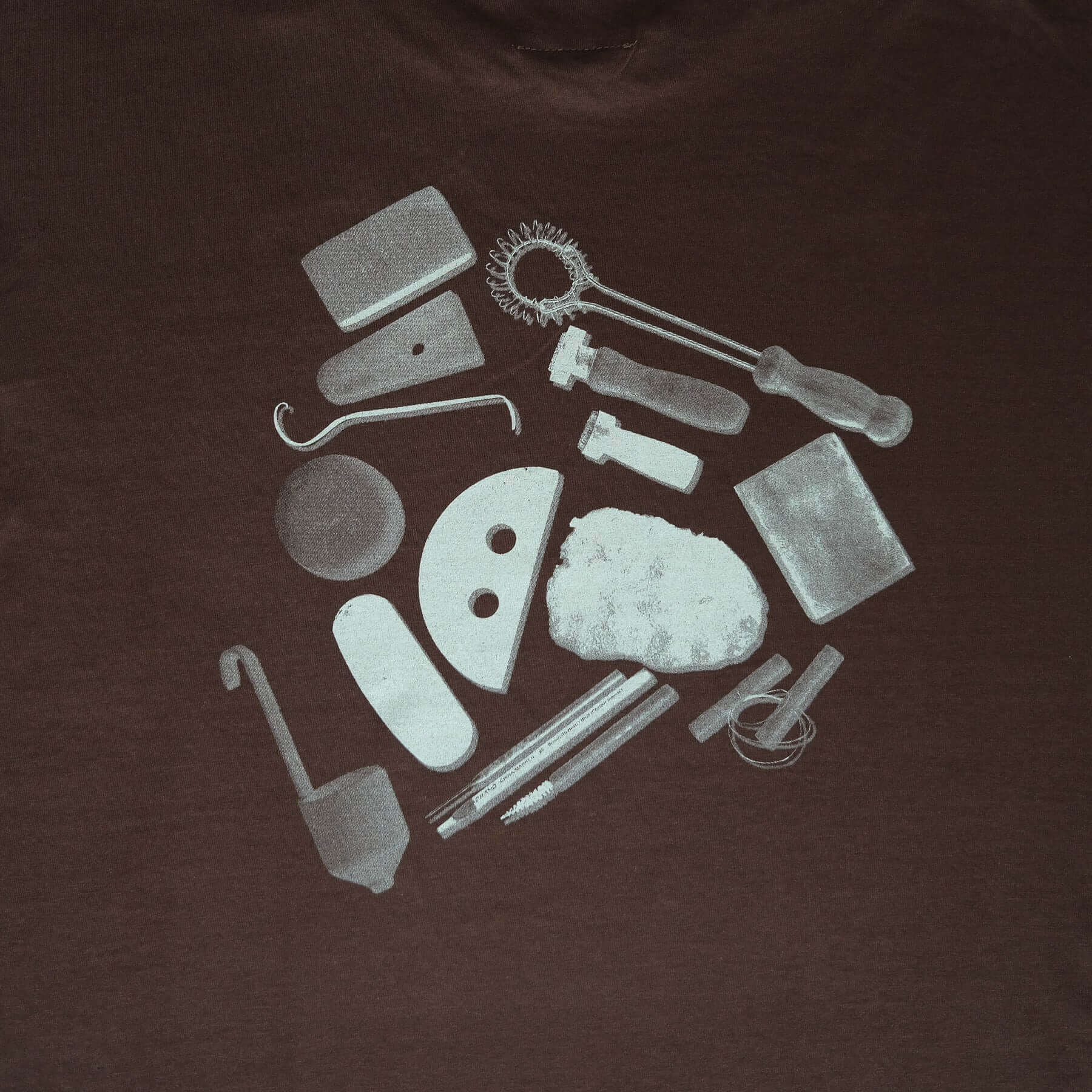 Back design of vbc Team Shirt featuring pottery tools printed in white on a chocolate background.