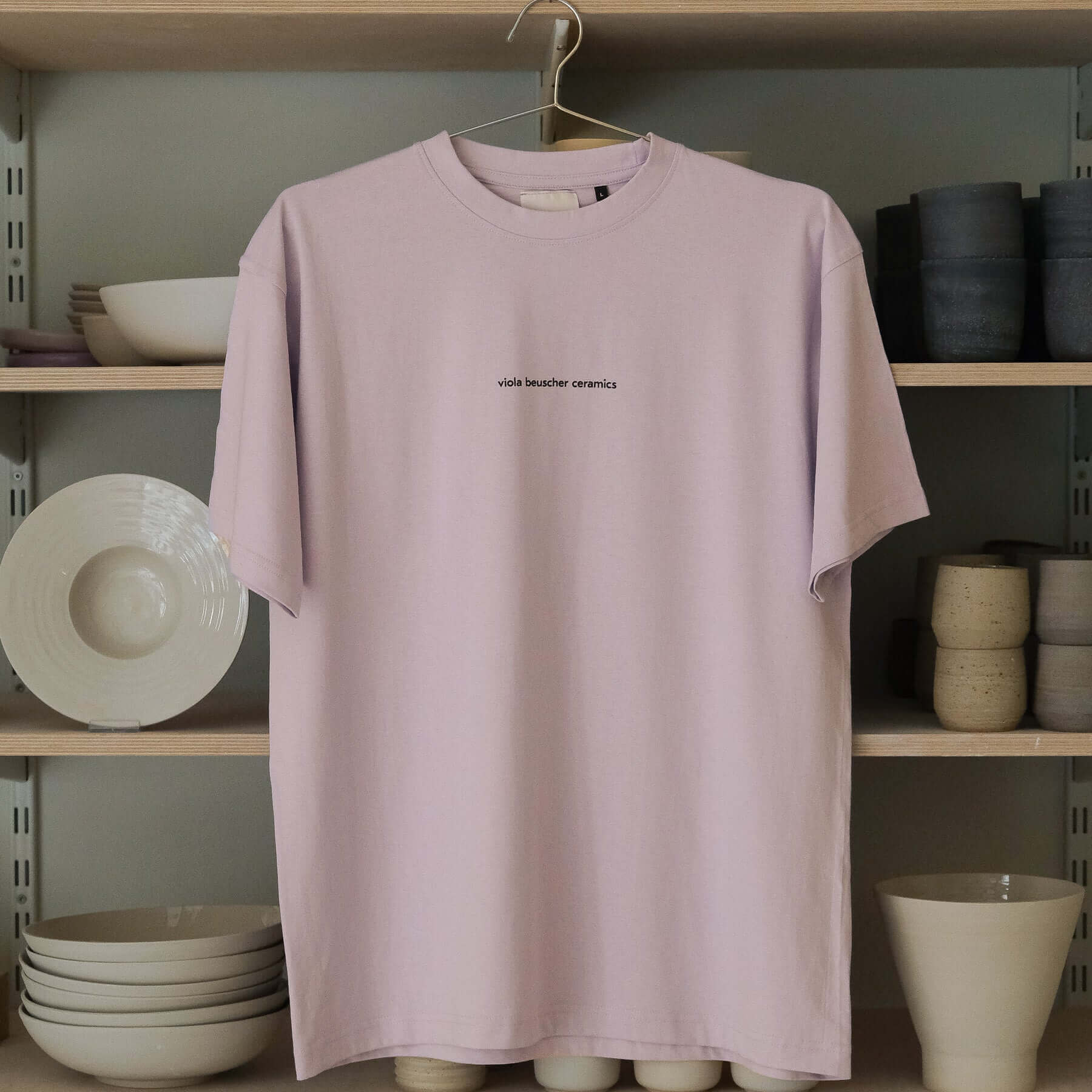 Lilac vbc Team Shirt hanging on a rack, showcasing a minimalist design with logo print.