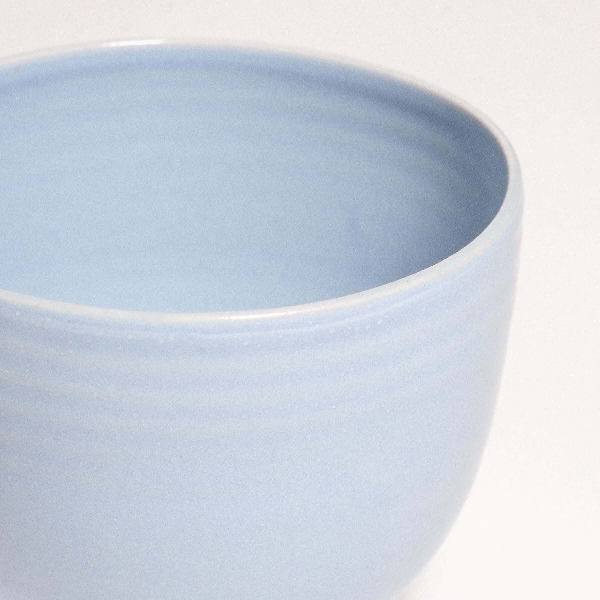 Close-up of a light blue stoneware coffee cup with smooth finish and subtle ribbed design.