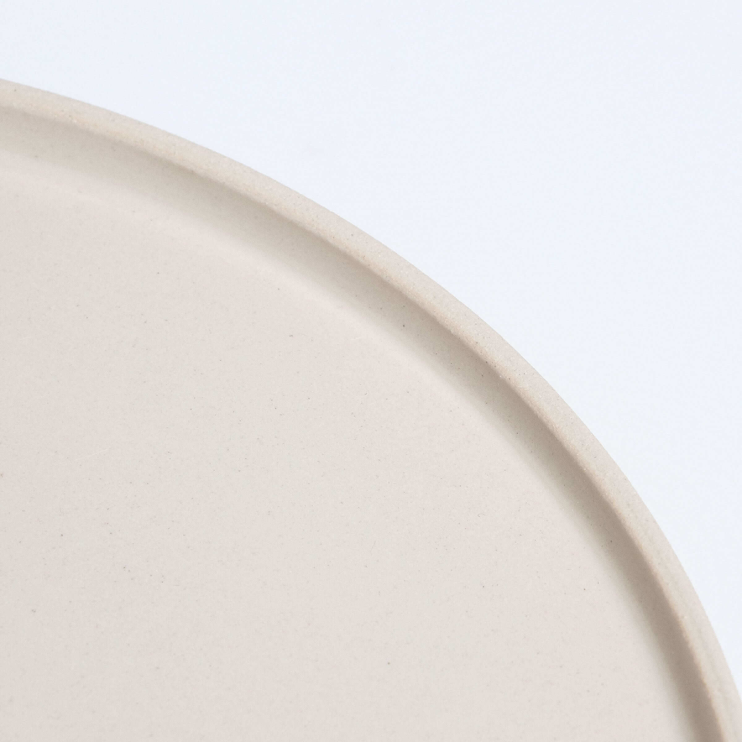 Close-up of a unique medium creme dinner plate, showcasing its smooth, handcrafted stoneware ceramic finish.