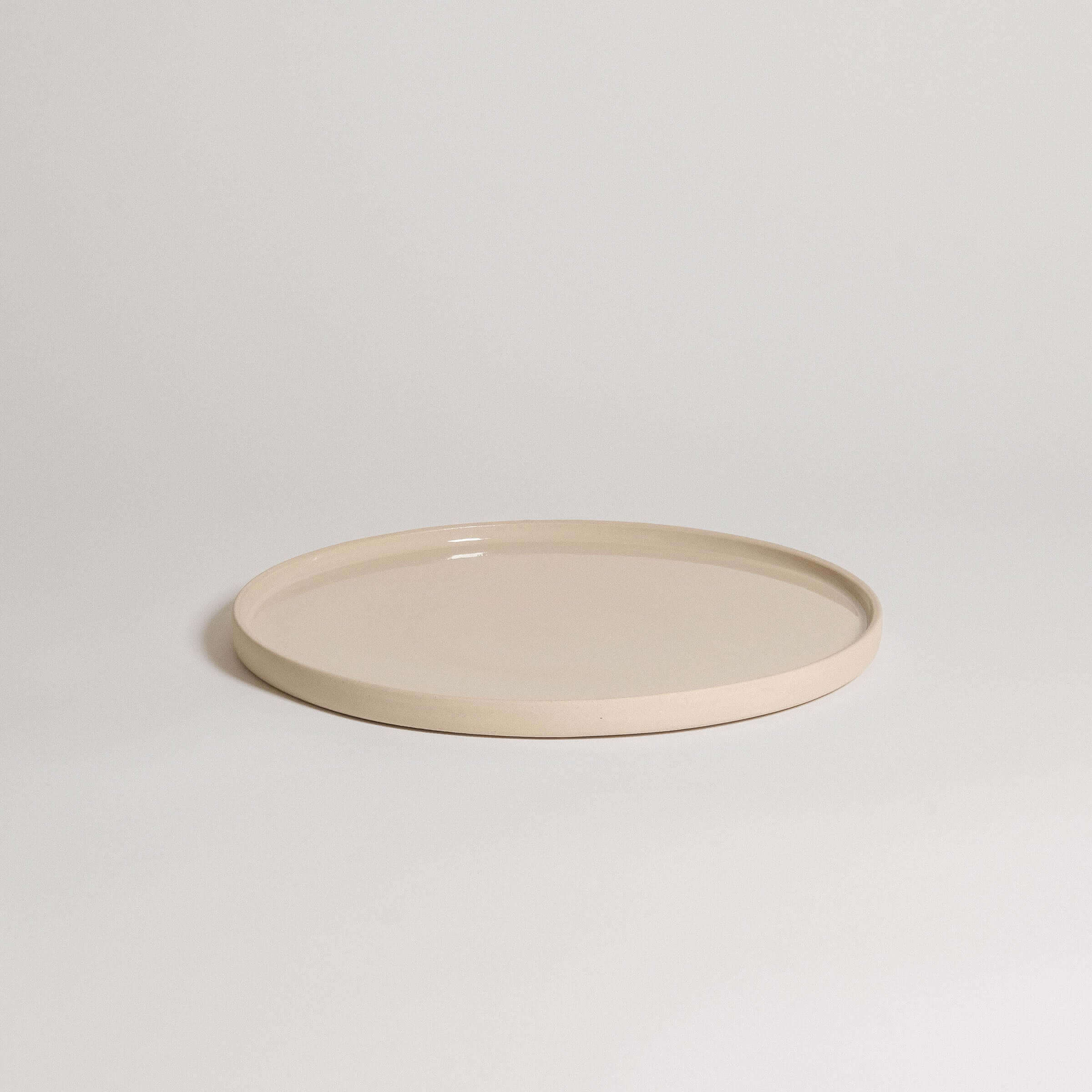 Unique creme dinner plate handcrafted from durable stoneware ceramic with a glossy finish.