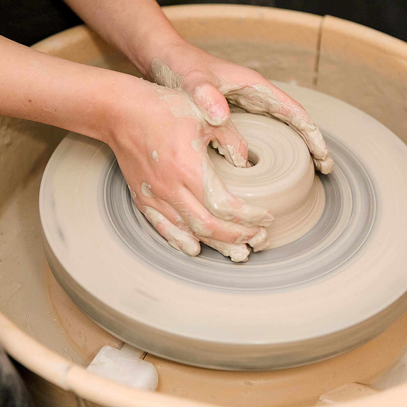 Hands shaping clay on a pottery wheel during a Gift Making Class.