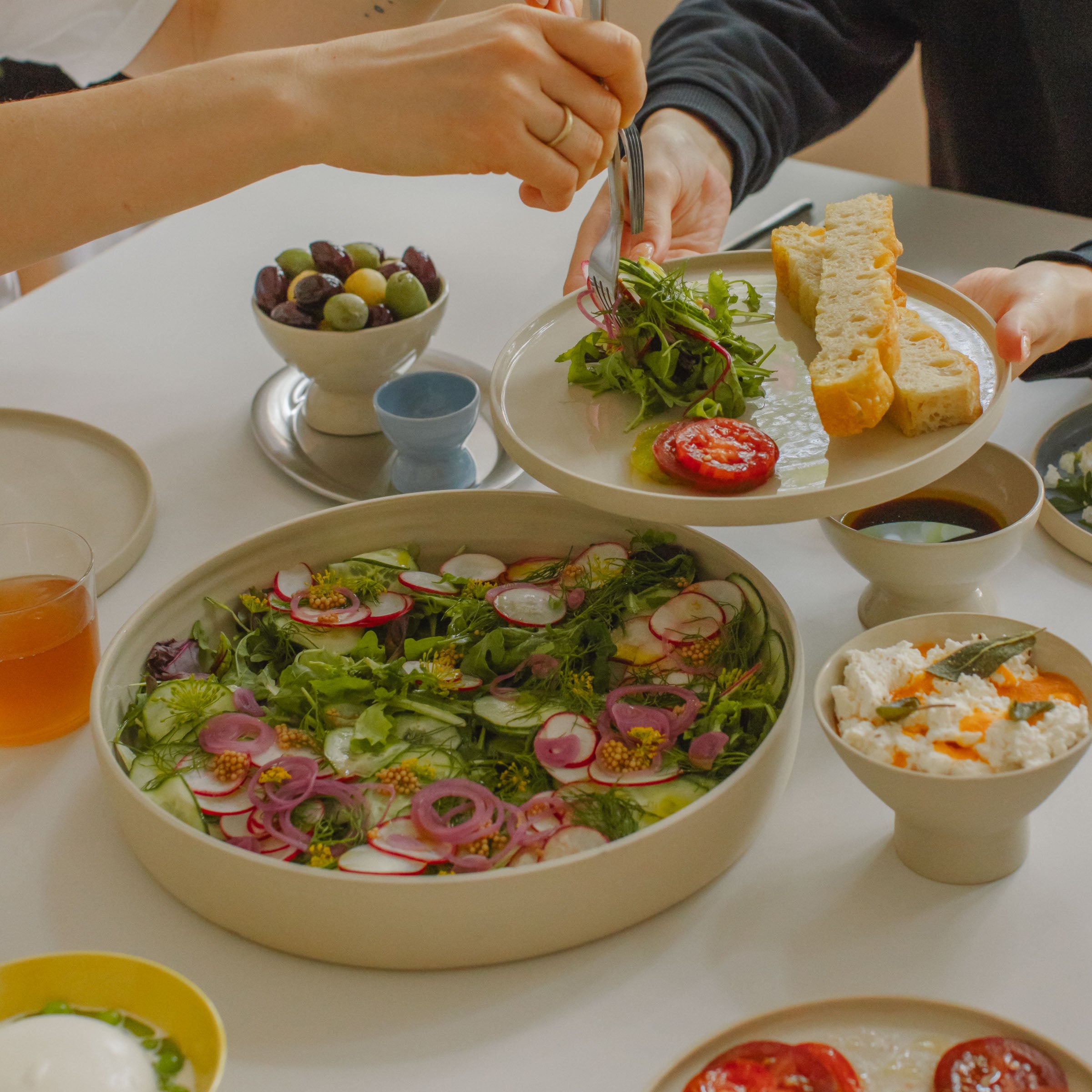 Serving fresh salad and bread on a unique handcrafted creme dinner plate, highlighting natural ceramic beauty.