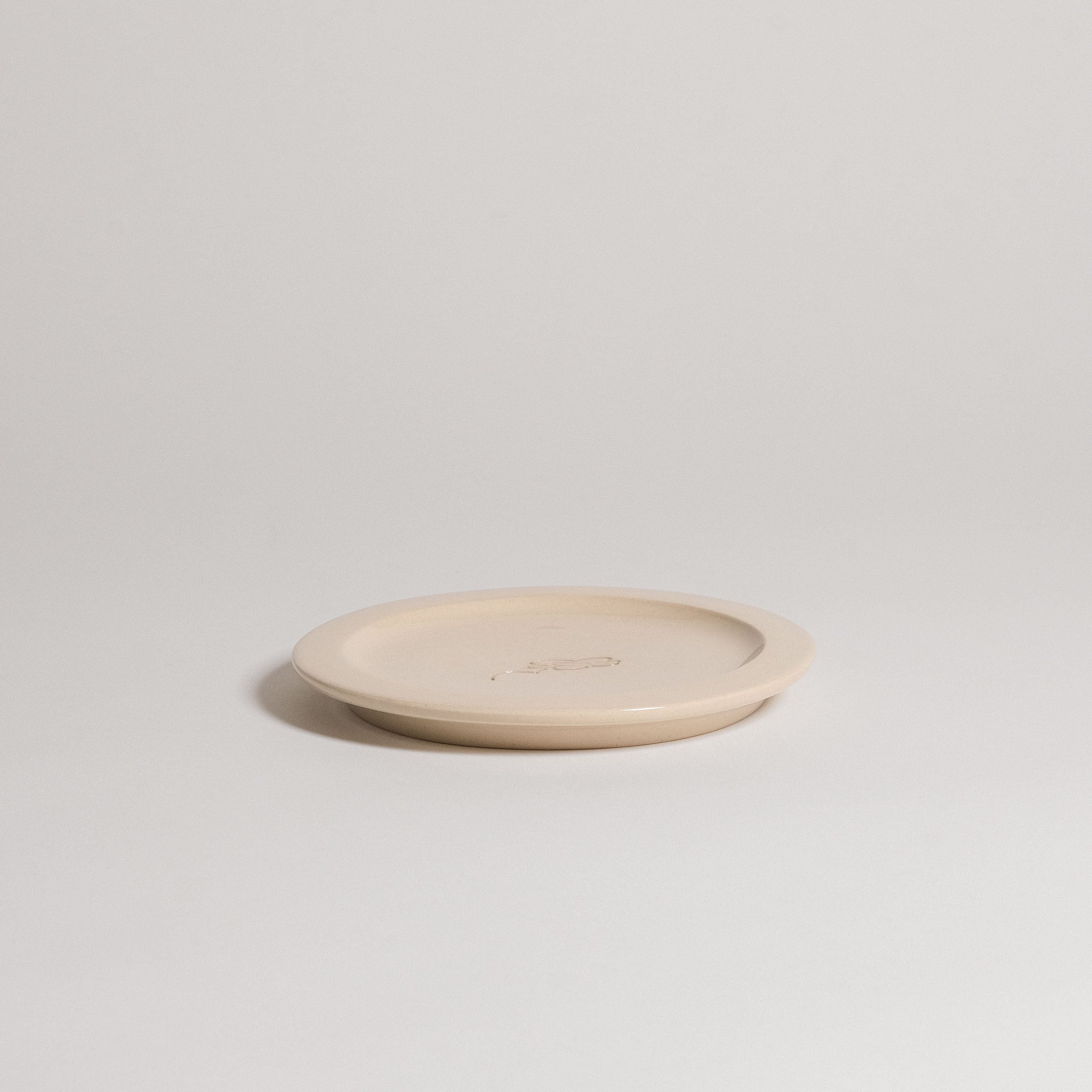 Handcrafted Neo Creme bistro plate in durable stoneware with embossed logo, showcasing transparent glaze and unique character.