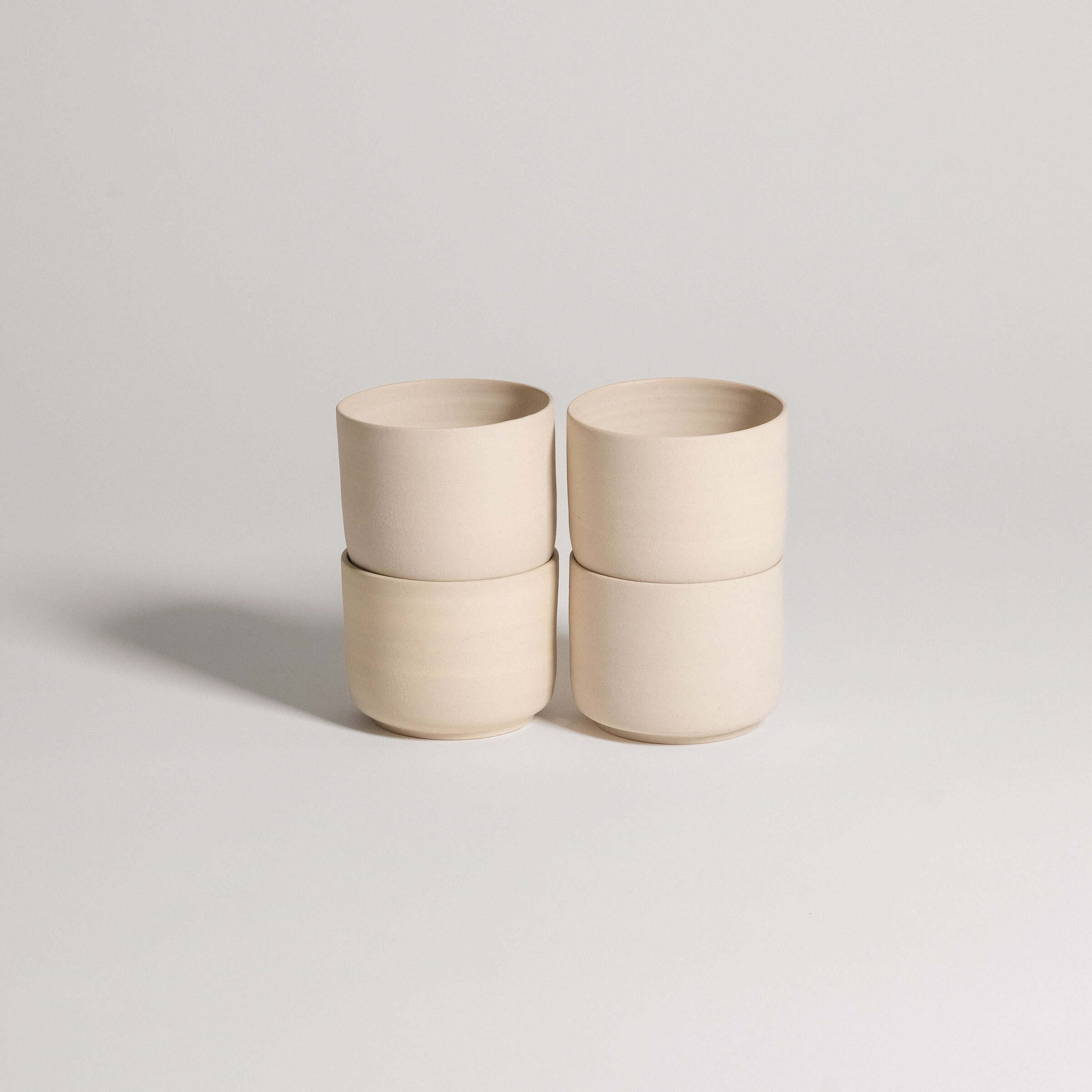 Set of 4 Nomi Creme coffee cups in grey stoneware with glossy interior glaze and raw exterior.