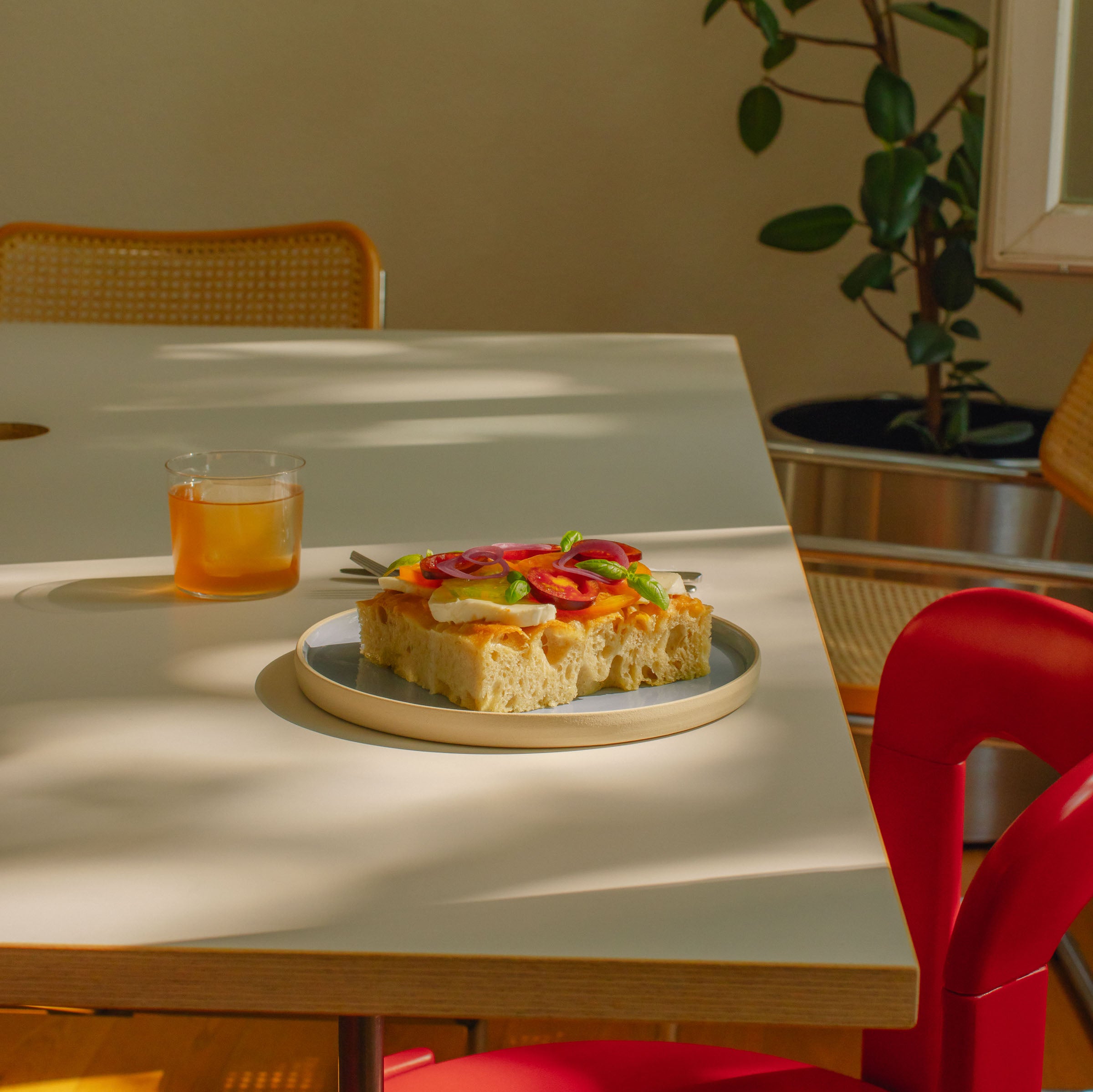 A delicious sandwich on a medium Iceblue dinner plate, set on a stylish dining table with a drink.