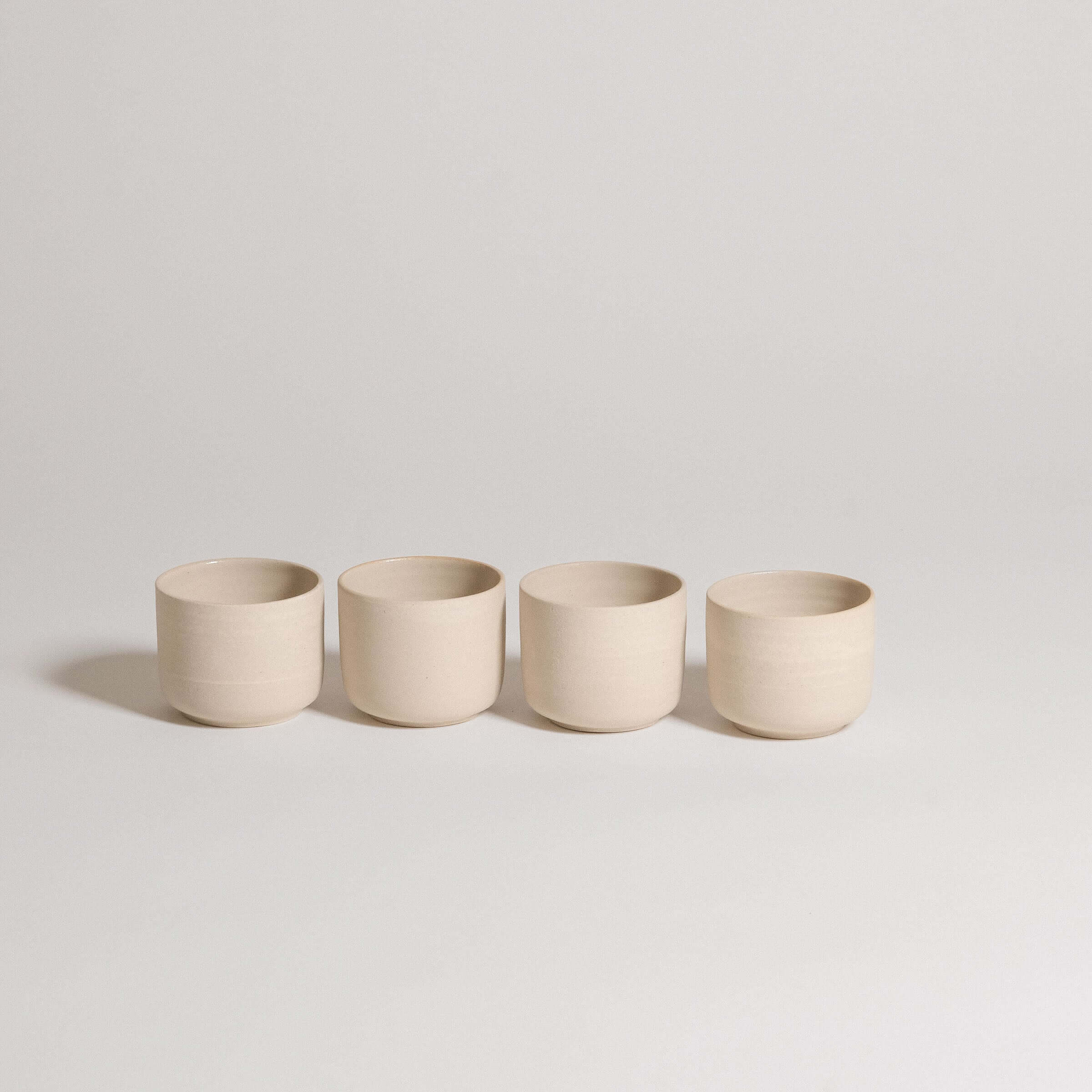 Set of 4 Nomi Creme espresso cups in grey stoneware with glossy glaze interior and raw exterior.
