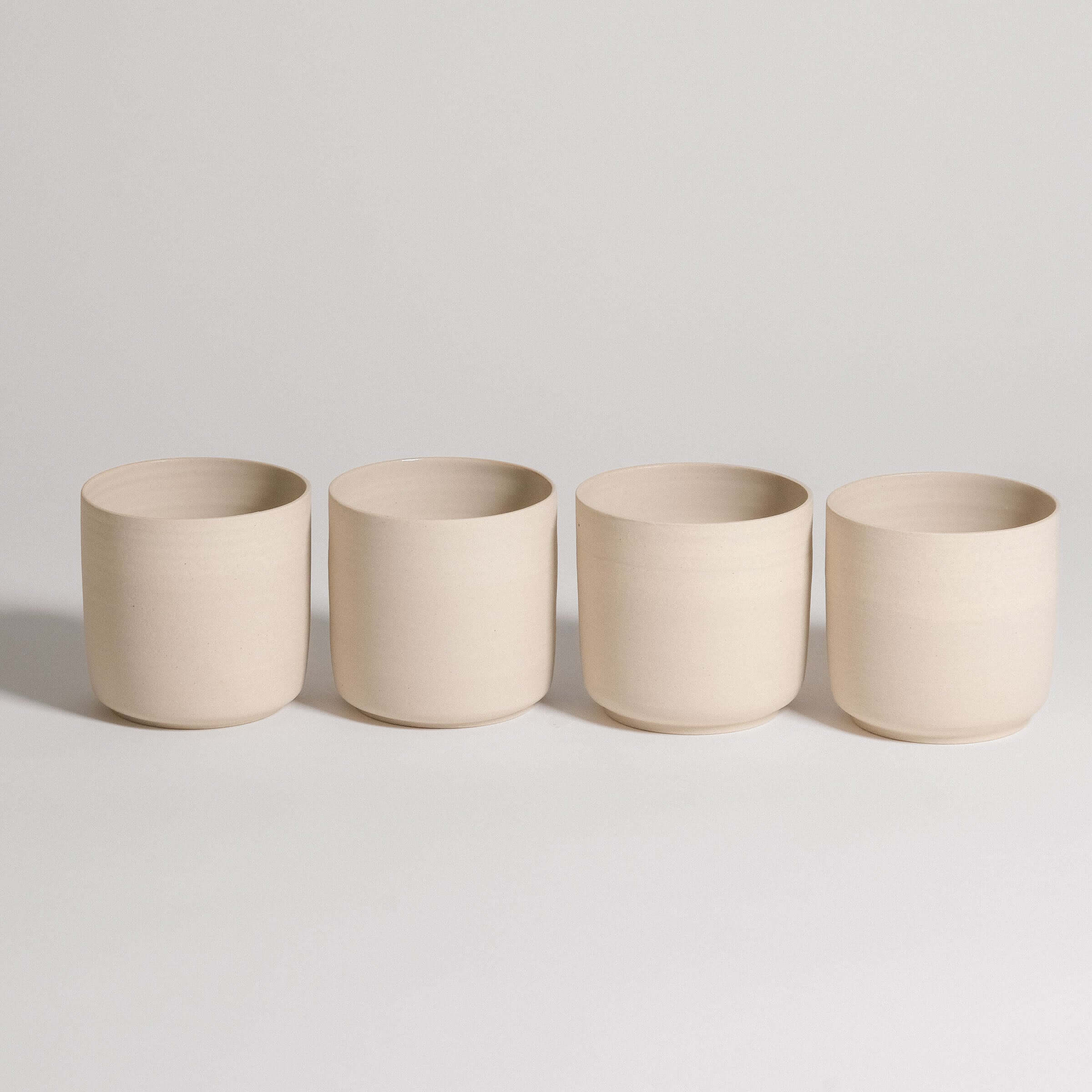 Set of 4 tea cups in Nomi Creme, crafted from grey stoneware with a glossy interior and raw exterior finish.