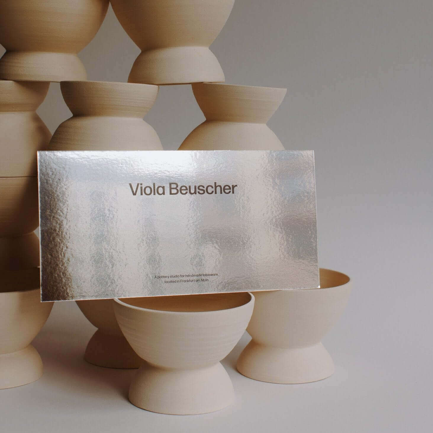 Printed gift card displayed in front of sculptural wooden bowls, featuring minimalist design.