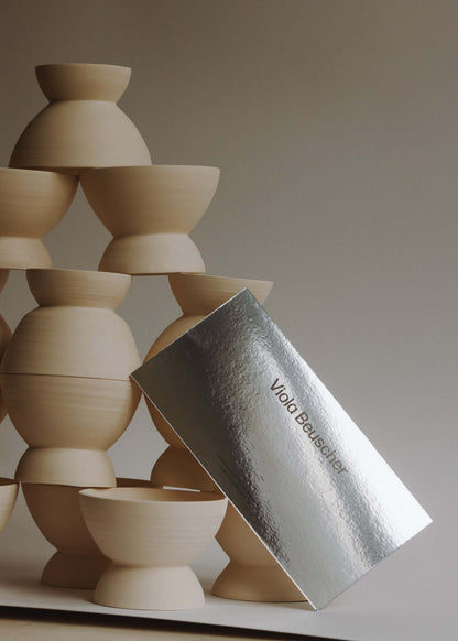 Printed gift card beside stacked wooden pottery bowls in a minimalist setting.