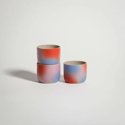 Handcrafted Dawn Espresso Cups in red, blue, and lilac gradient on grey stoneware clay.