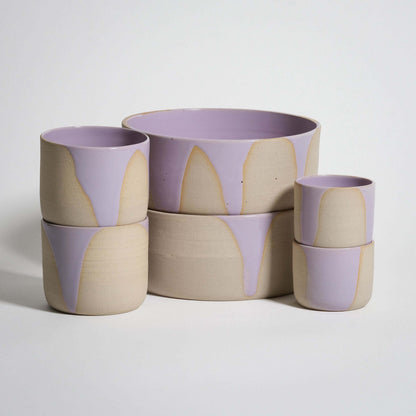Splash Lilac Tableware Set features handcrafted cups and bowls in glossy pink and lilac glazes, ideal for breakfast and beverages.