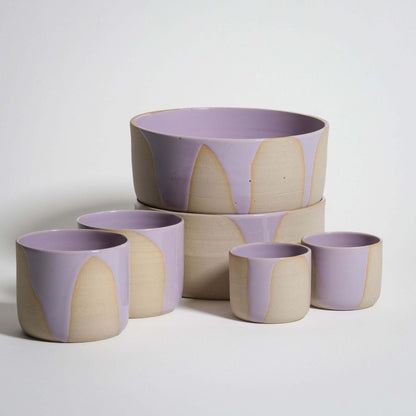 Splash Lilac Tableware Set featuring handcrafted espresso cups, coffee cups, and breakfast bowls in glossy pink and lilac glaze.