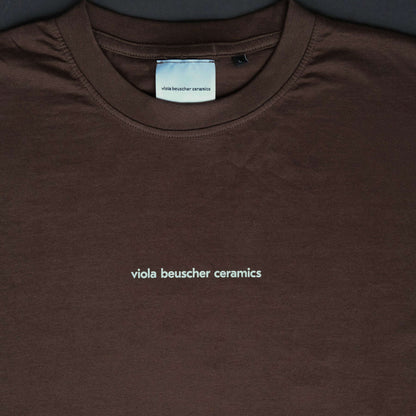 Chocolate T-shirt featuring white logo print 'viola beuscher ceramics' on the front.