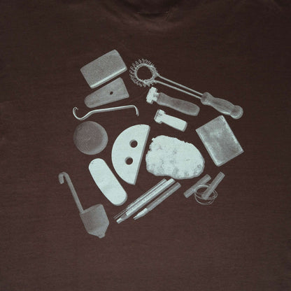 Back design of vbc Team Shirt featuring pottery tools printed in white on a chocolate background.