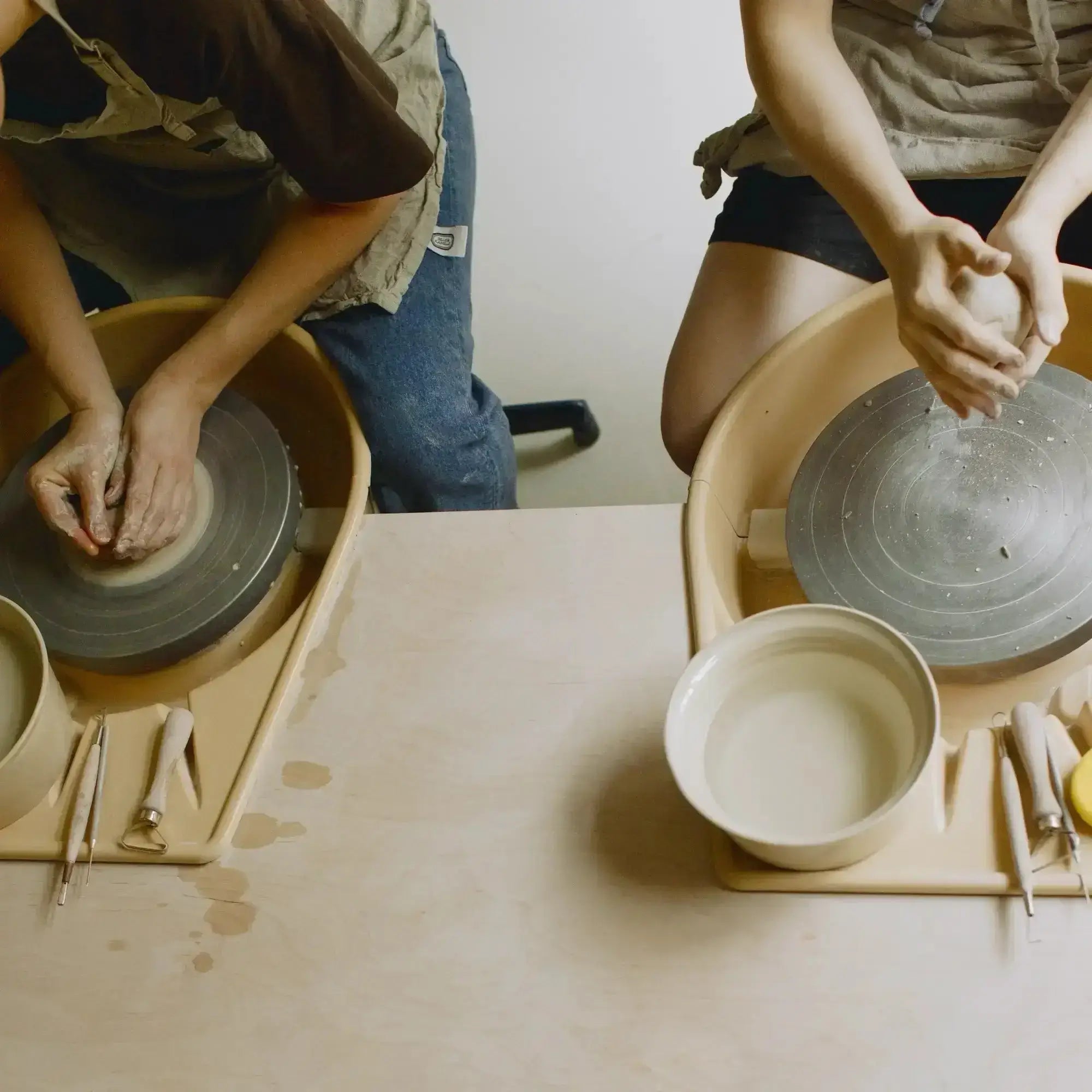 Participants learning pottery techniques at a beginner wheel class, focused on clay shaping.