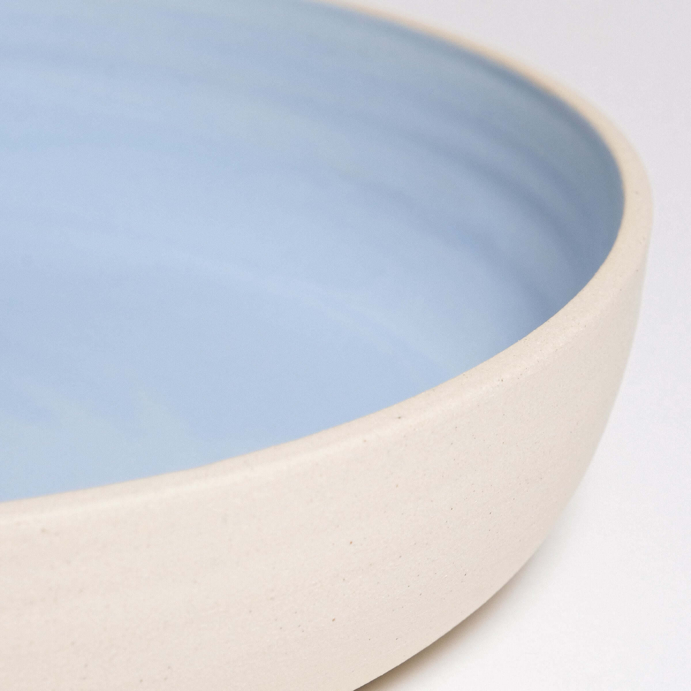 Close-up of handcrafted stoneware dinner bowl with elegant ice blue glaze, perfect for everyday use.