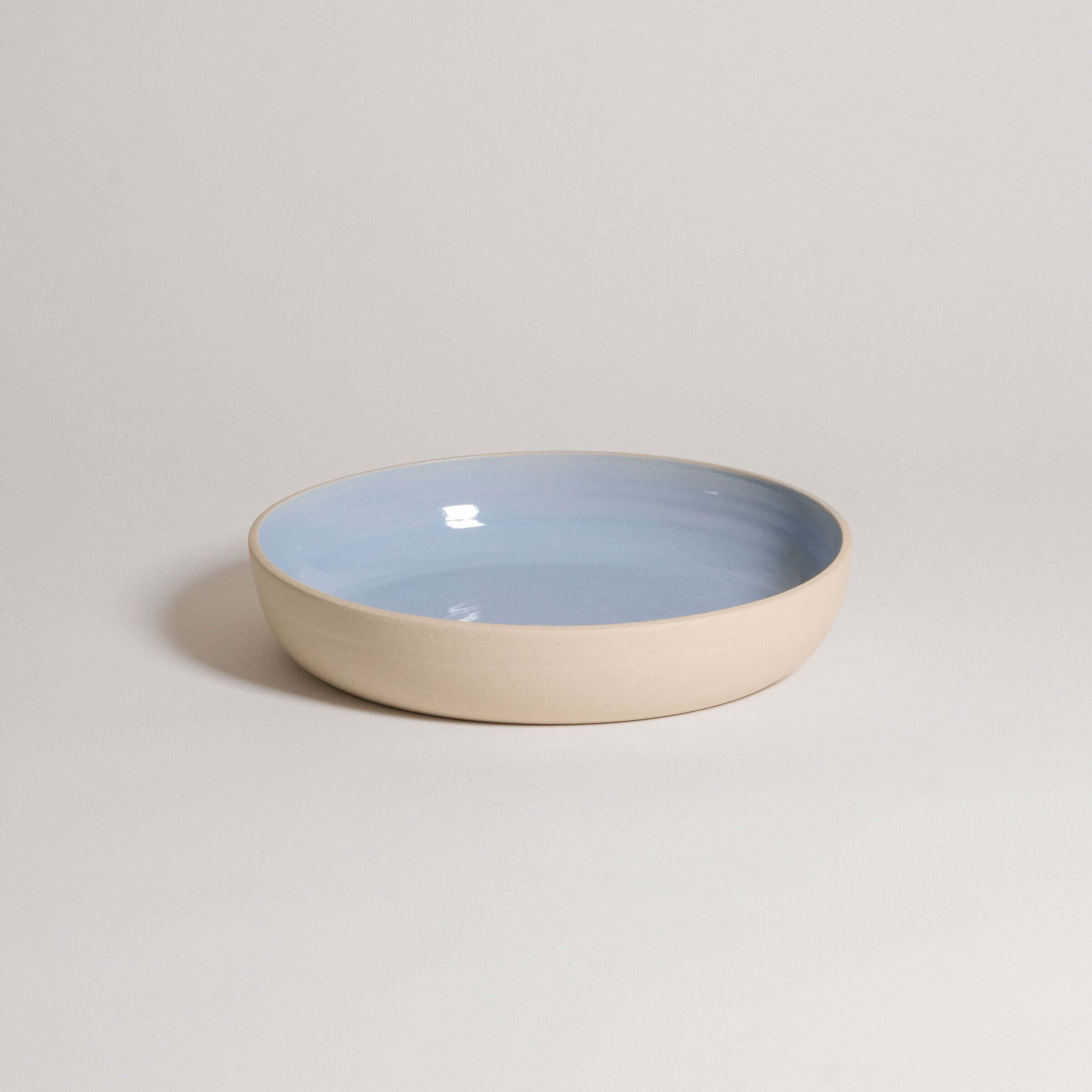 Handcrafted ice blue dinner bowl made from durable stoneware ceramic with a transparent glaze for elegance.