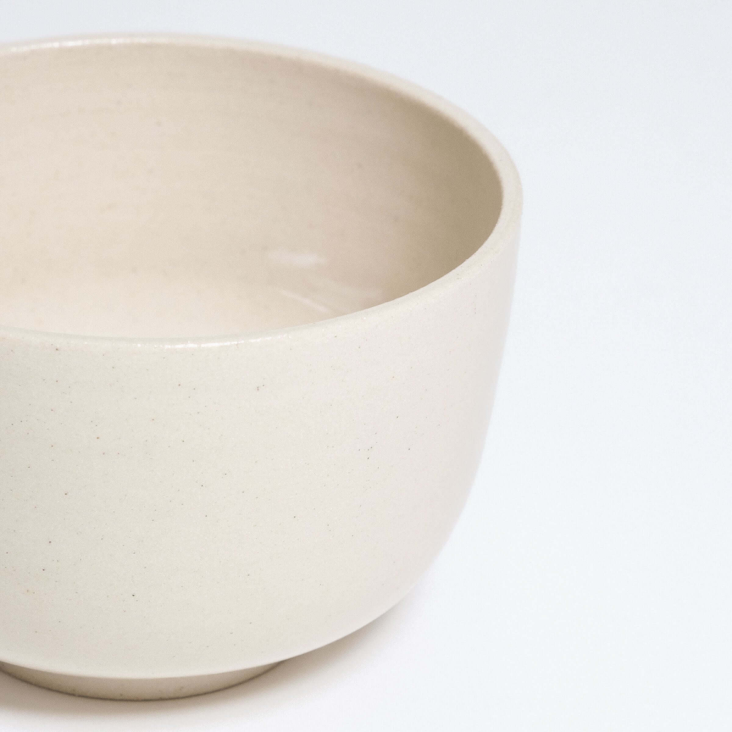 Glossy beige stoneware bowl with smooth surface, ideal for serving and showcasing culinary creations.