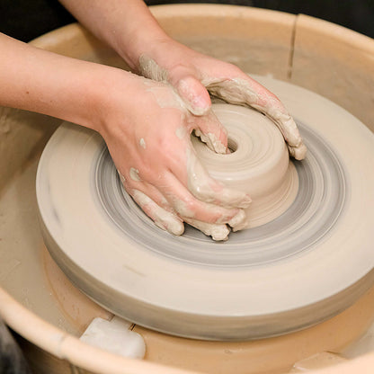 Hands shaping clay on a pottery wheel during a Gift Making Class.