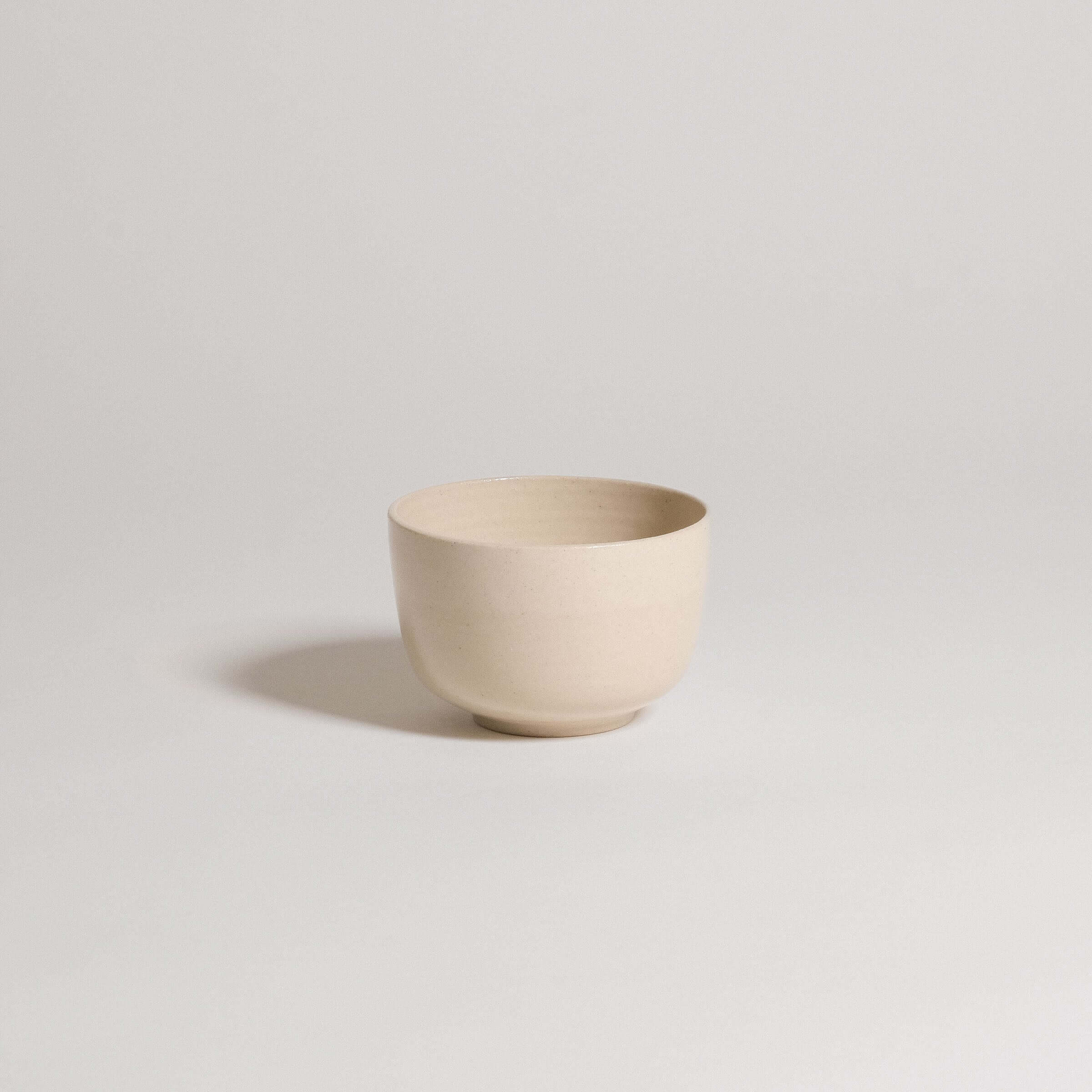 Cream-colored stoneware bowl with a smooth finish, ideal for serving food or decorative use.