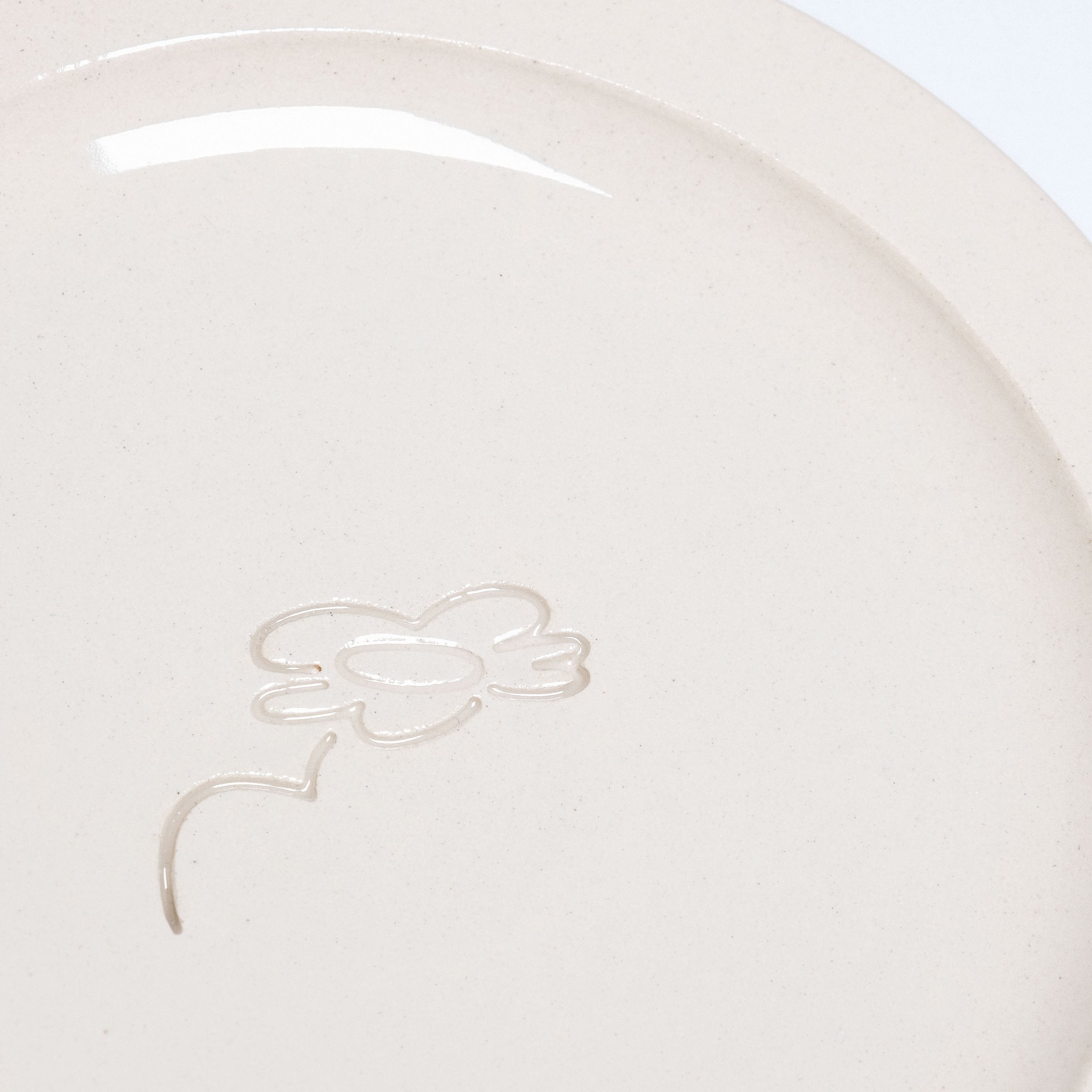 Close-up of neo creme bistro plate showcasing embossed logo and smooth glaze finish on durable stoneware.