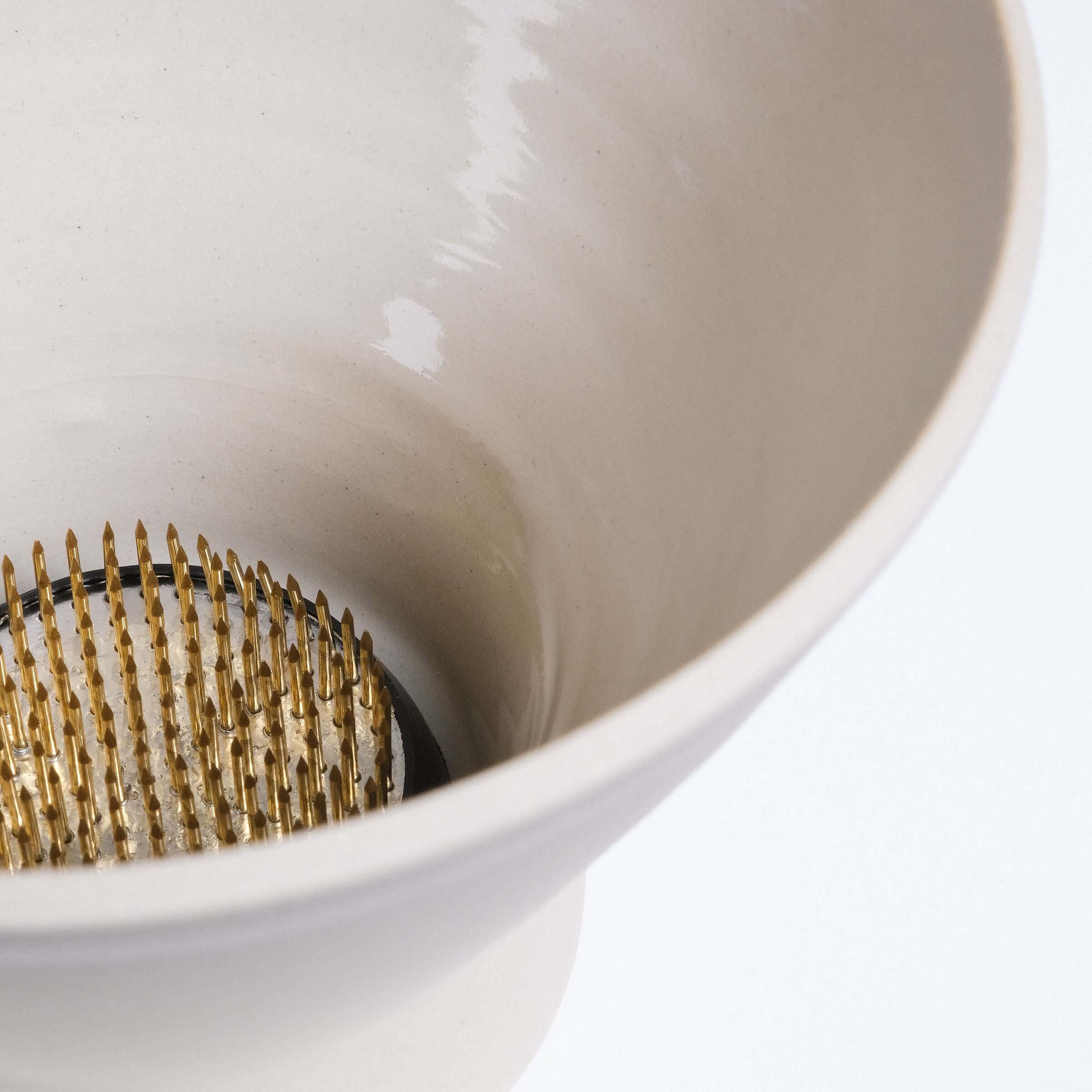 Ikebana vase interior showing golden kenzan on grey stoneware, perfect for floral arrangements.