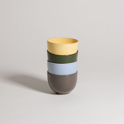 Colorful stack of cups from the Mix & Match - Cup & Mug Bundle, featuring yellow, green, blue, and brown.