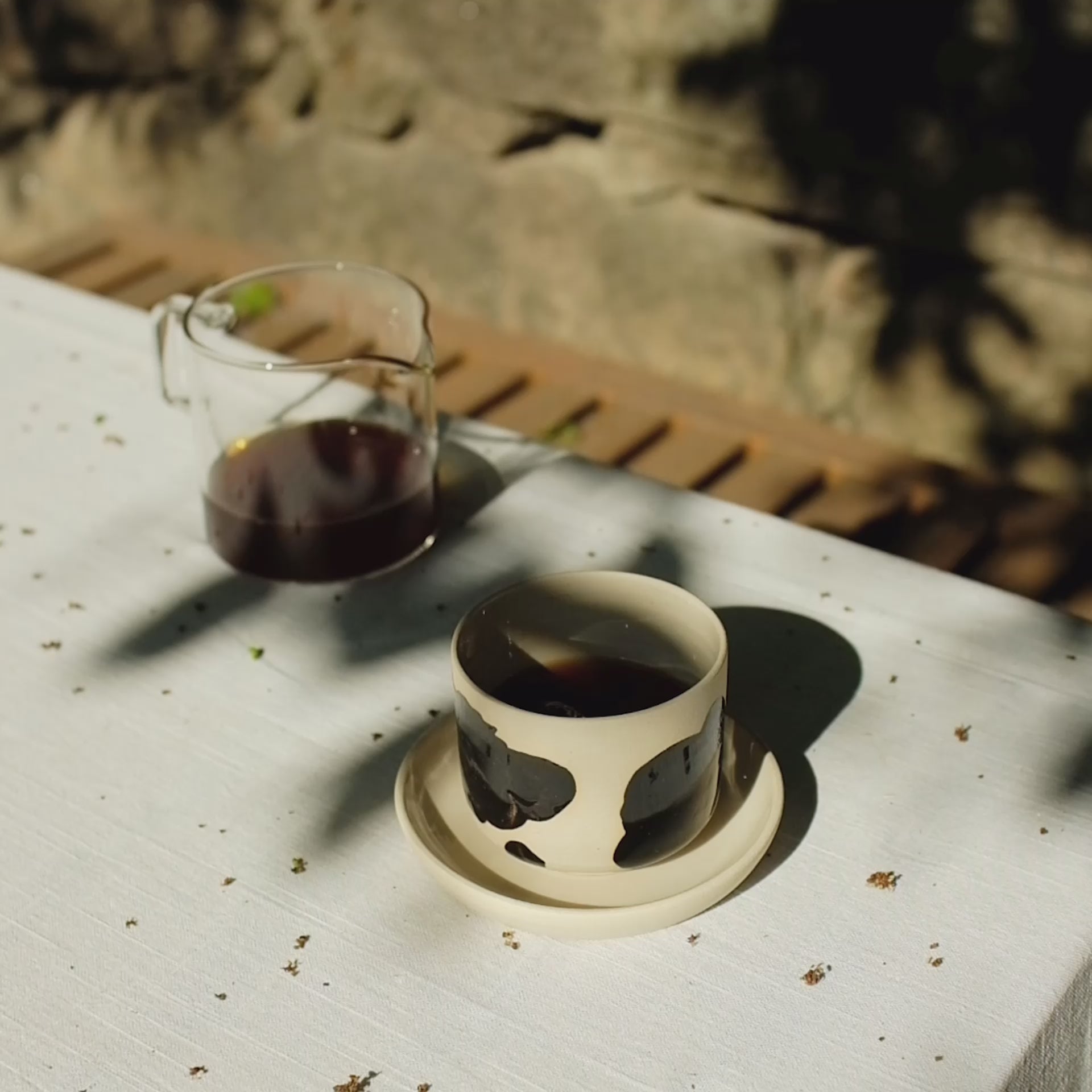 Video laden: Set of 4 Nomi Pepe coffee cups on a table, showcasing grey stoneware with glossy black brush strokes and clear glaze.