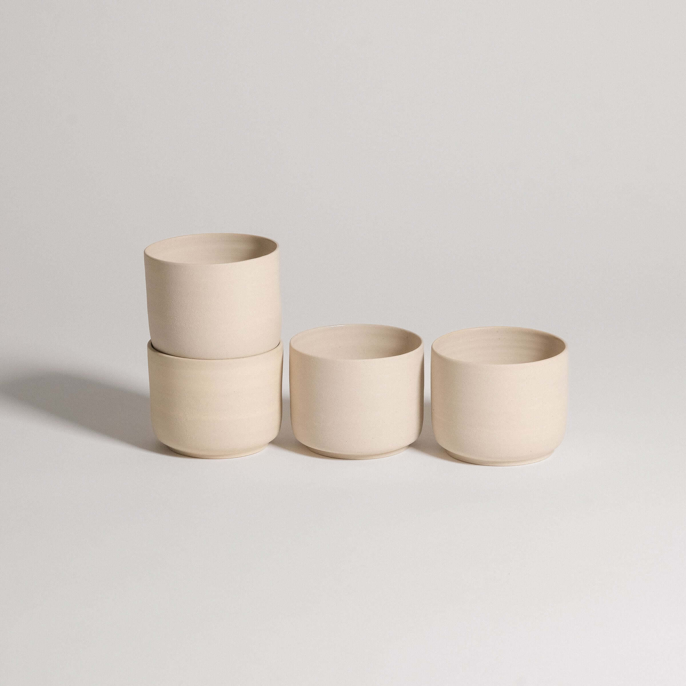 Set of 4 Nomi Creme coffee cups in grey stoneware with glossy glaze interior and raw exterior finish.