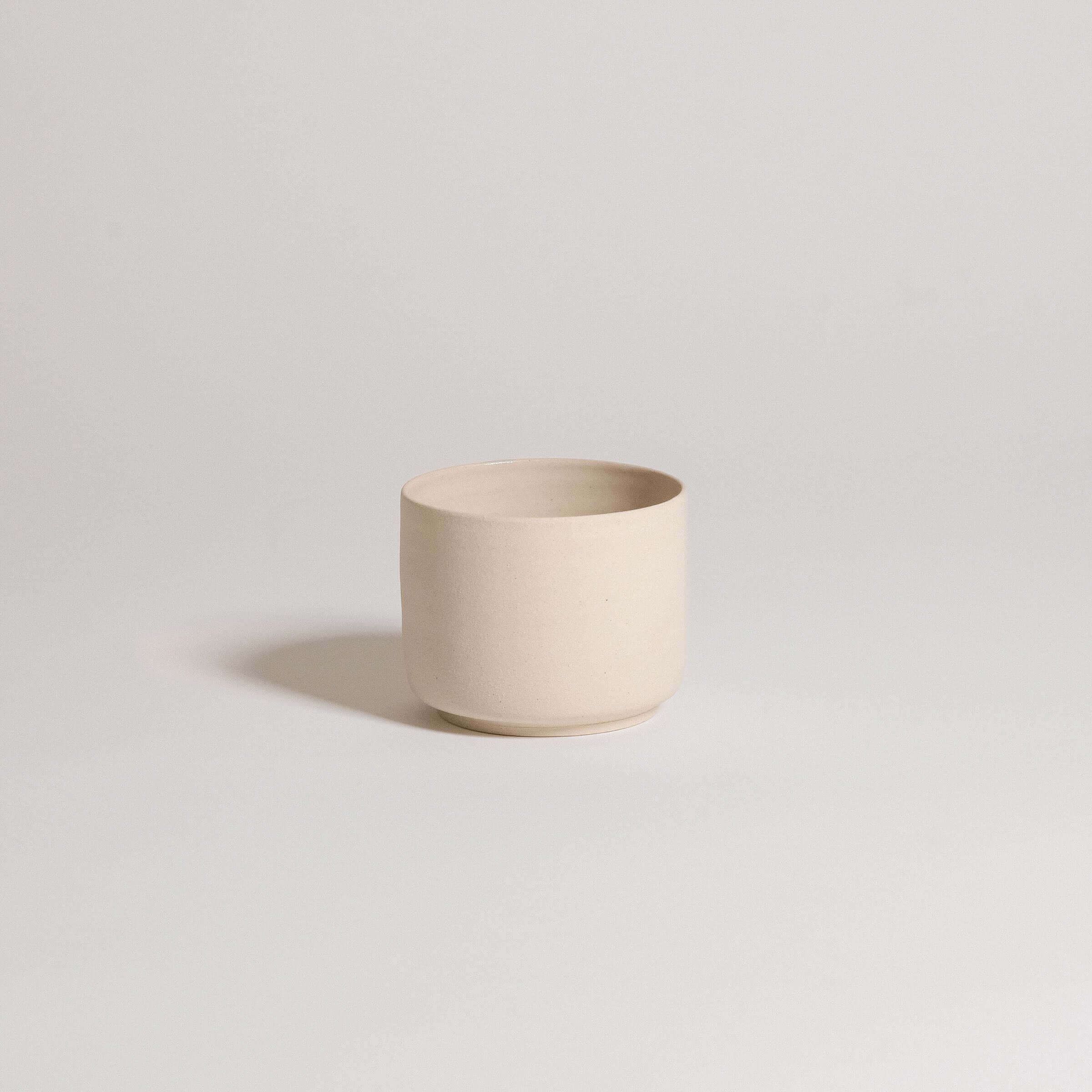 Set of 4 Nomi Creme coffee cups in gray stoneware with glossy interior and raw exterior.