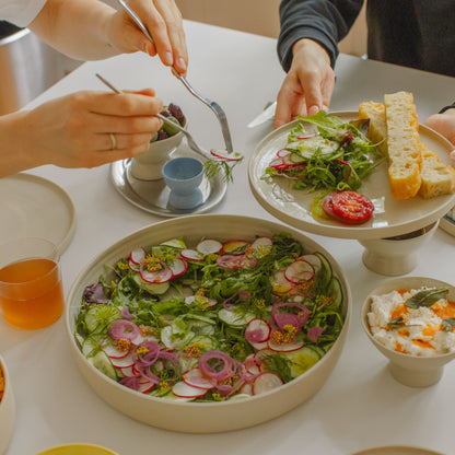 Set of 4 creme dinner plates with salad and bread on a dining table, showcasing handcrafted stoneware.