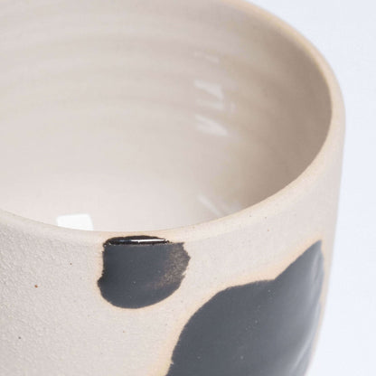 Close-up of a Nomi Pepe espresso cup featuring hand-painted black brush strokes and glossy interior glaze.