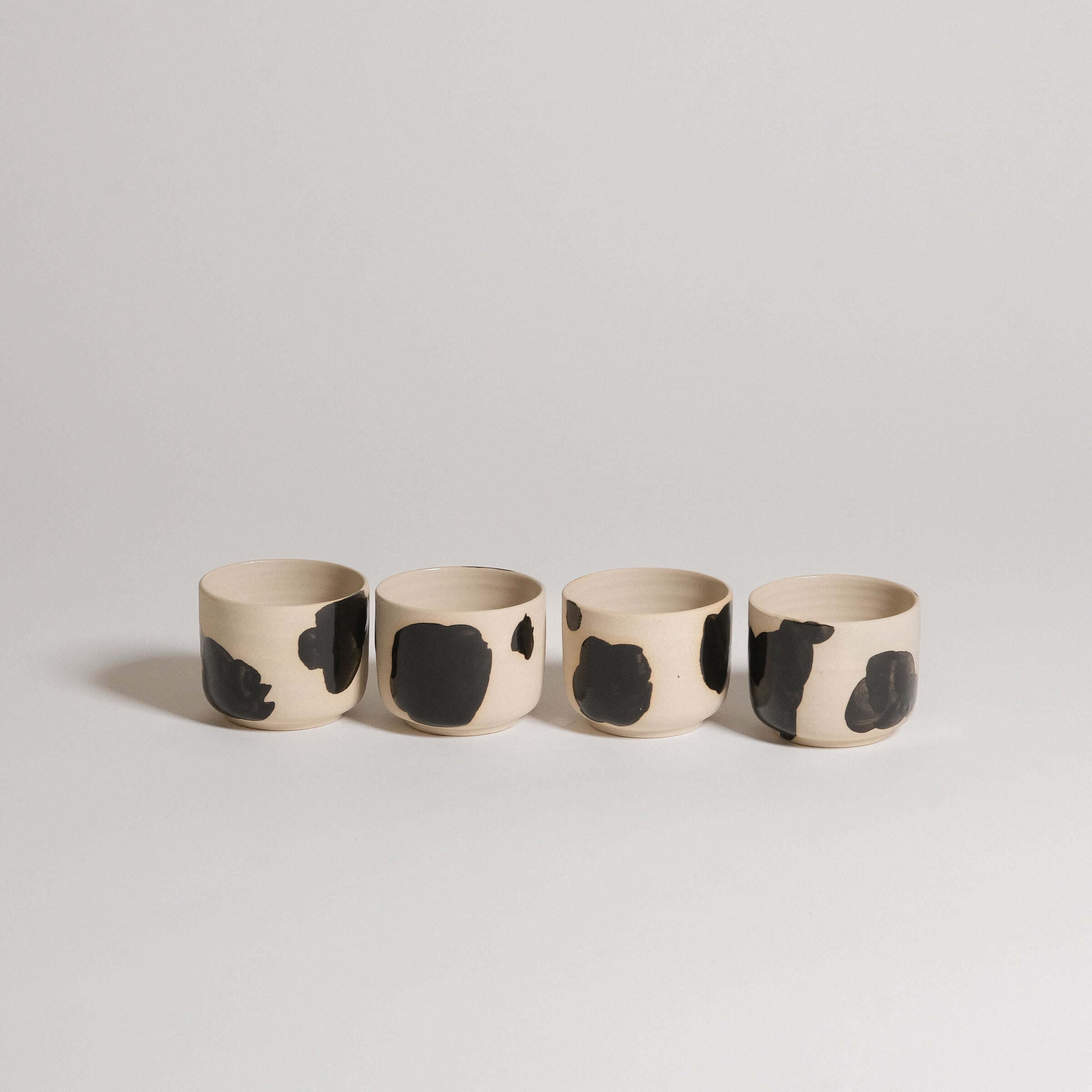 Set of 4 Nomi Pepe espresso cups in grey stoneware with glossy black hand-painted accents.
