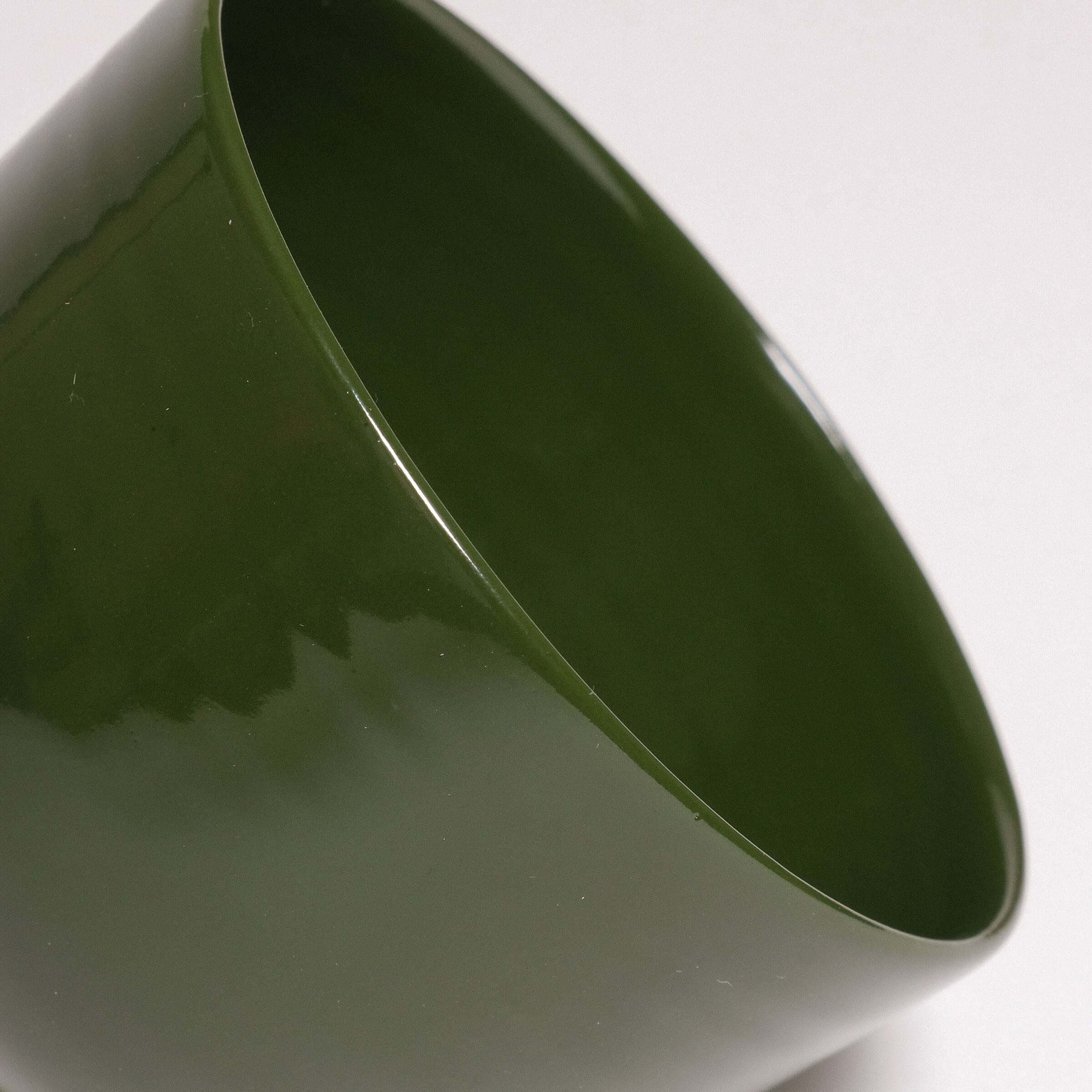 Close-up of Yun Green coffee cup made from stoneware ceramic with a glossy green glaze.