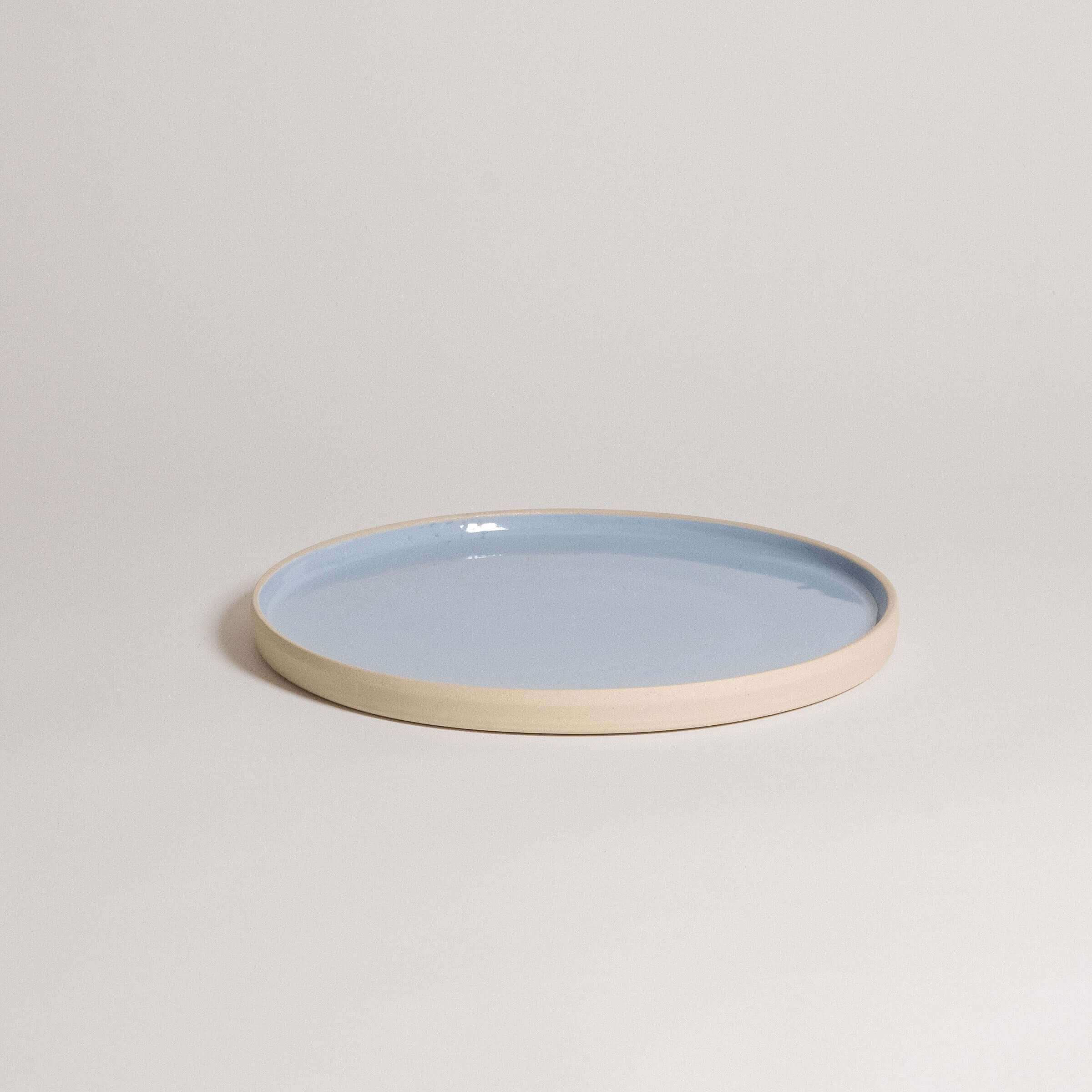 Handcrafted medium dinner plate in ice blue glaze with a natural stoneware base, dishwasher and oven safe.