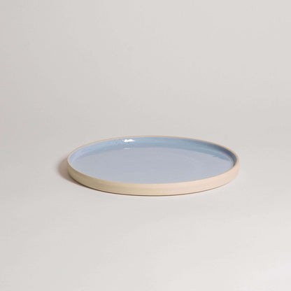 Handcrafted medium dinner plate in ice blue glaze with a natural stoneware base, dishwasher and oven safe.