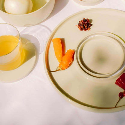 Handgefertigtes Tapas-Tablett in creme mit bunten Paprika und Getränk auf Tischdecke.